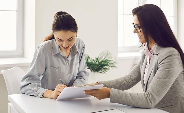 two women signing a contract or job offer