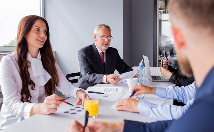 Program Manager Job Description: Essential Skills Guide Independent Recruiter LLC | Staffing Agency group-office-workers-table-meeting