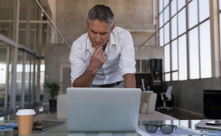 man thinking in front of a laptop