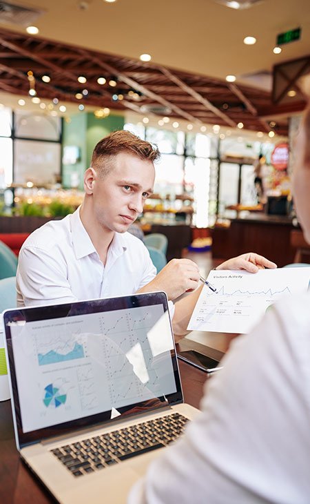 two-workers-discussing-statistics-laptop