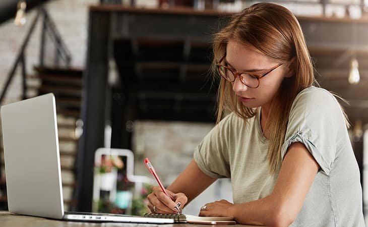 woman-writing-pen-laptop