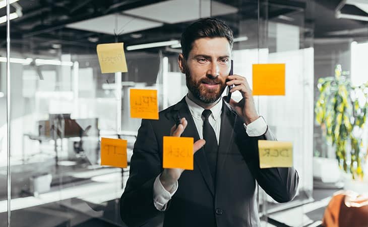 man-executive-phone-post-its-glass