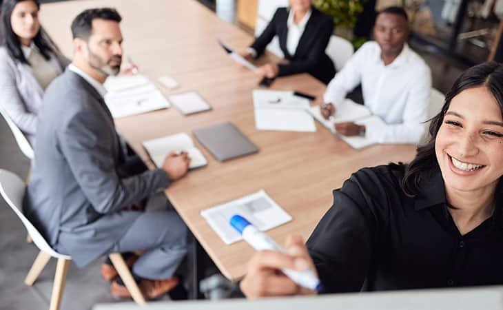 smiling woman writing in a board in a meeting