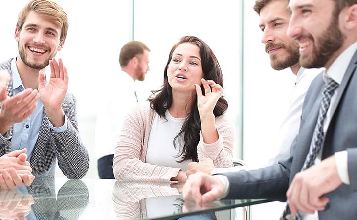 a woman making gestures and talking with people in an office