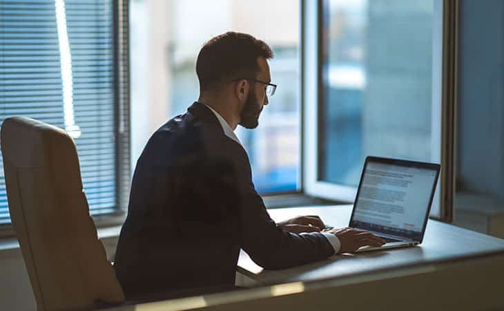 man in a suit and glasses using a laptop