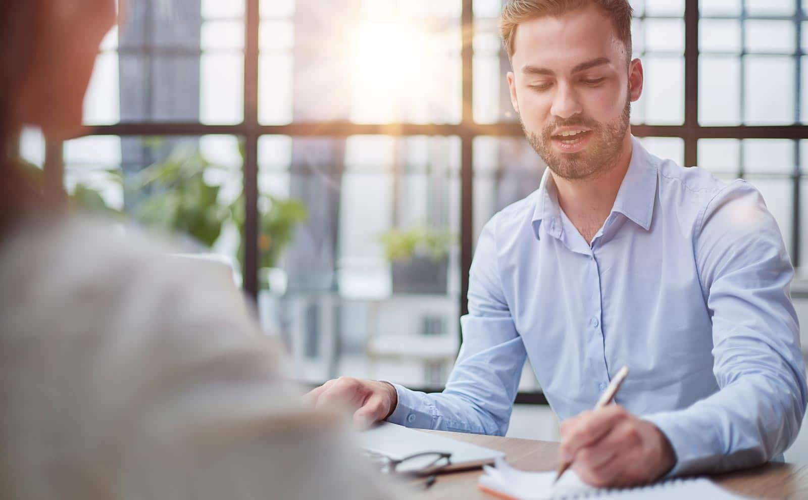 man taking notes while talking to a woman