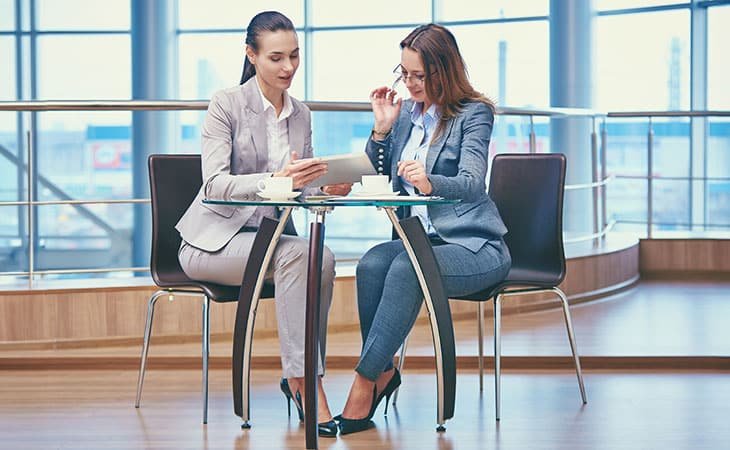 two women talking at the glass table