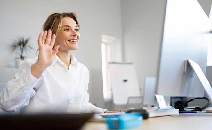 woman waving at the computer screen