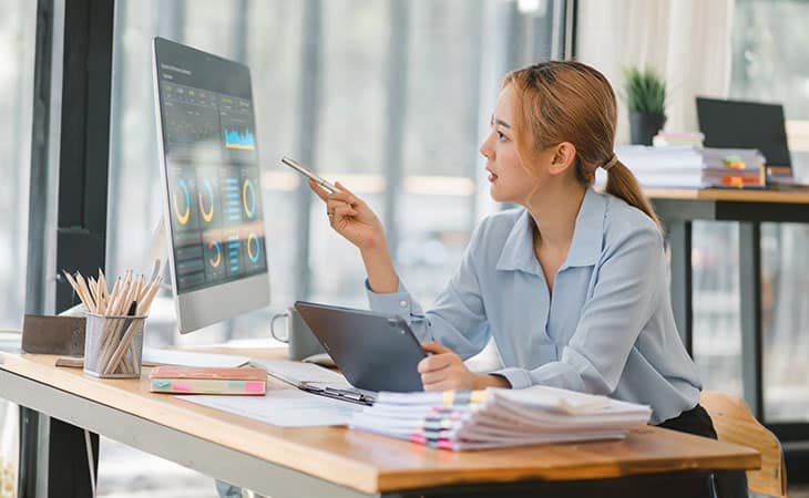 a woman in an office pointing at a screen