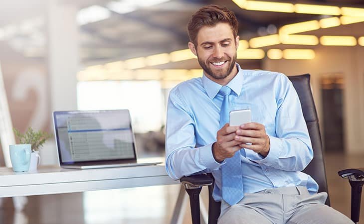 smiling-man-using-phone-email-laptop