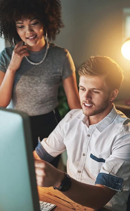 a woman and a man discuss something looking at a computer