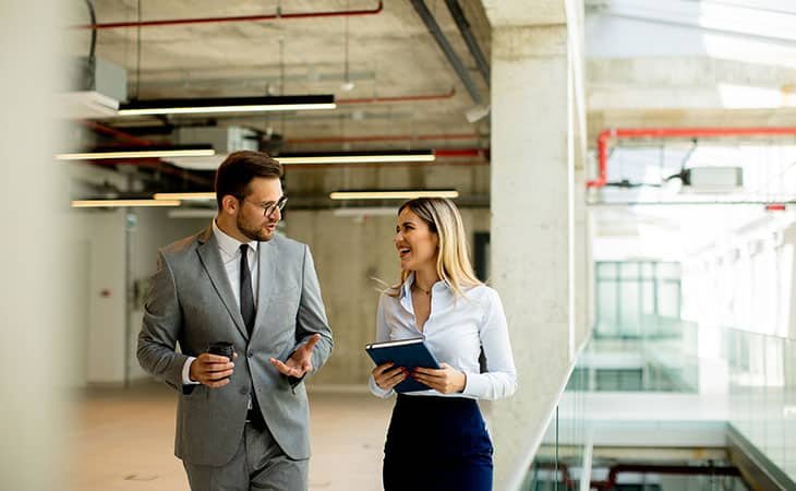a woman and a man talking in a building corridor
