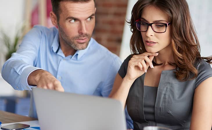 man talking to a woman and pointing at the computer