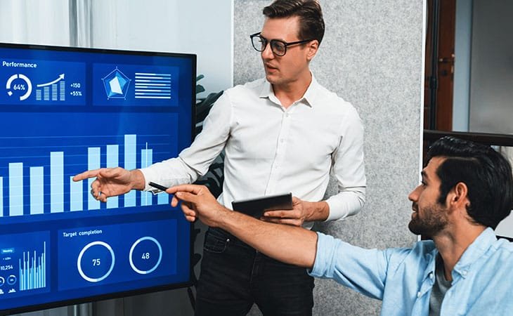 two men pointing at stats