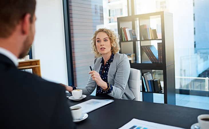 woman pointing with her pen talking to a man